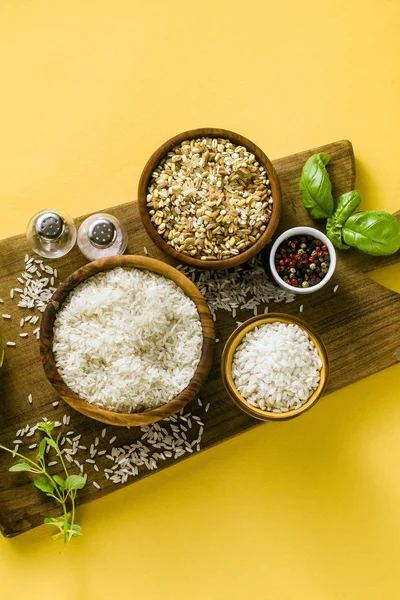 Different types of rice on a wooden board made from olive wood.