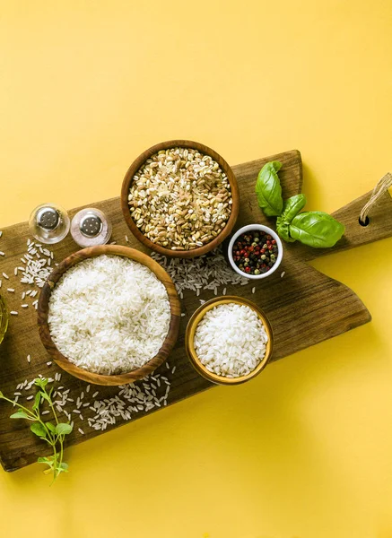 Different types of rice on a wooden board made from olive wood.