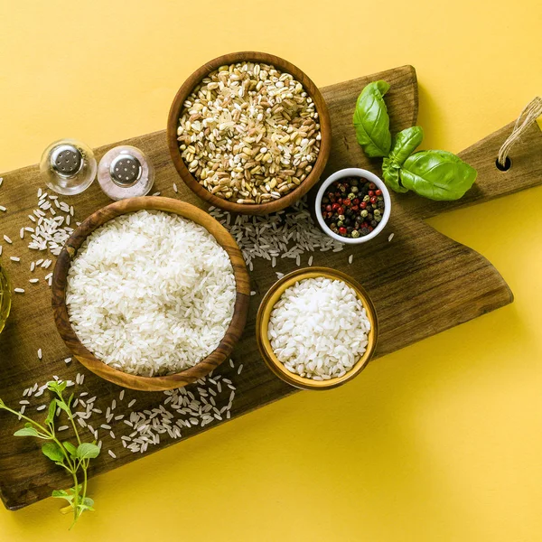 Different types of rice on a wooden board made from olive wood.
