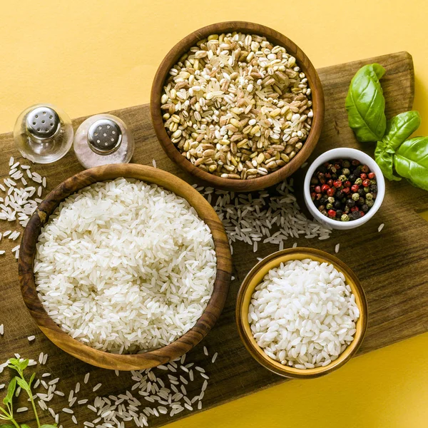 Different types of rice on a wooden board made from olive wood.