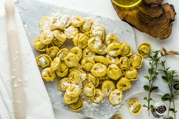 Rauwe ravioli tortellini op tafel met bloem en deegroller. — Stockfoto
