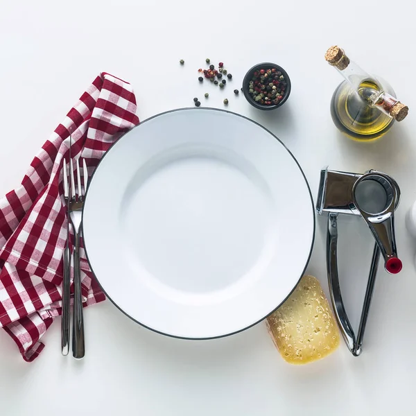 Blanco esmaltado plato vacío en la mesa con una na a cuadros rojo — Foto de Stock