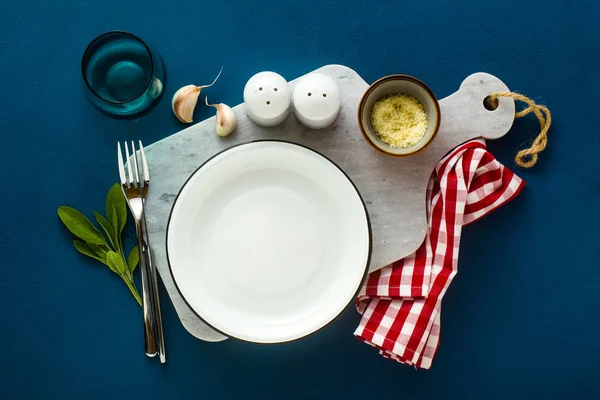 Plato servido vacío sobre tabla de servir de mármol y backgr de especias azules — Foto de Stock