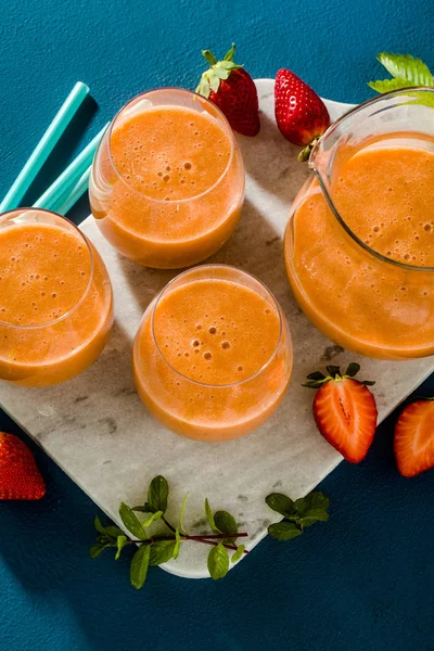 Batidos de fresa en una jarra y vasos sobre un fondo azul — Foto de Stock