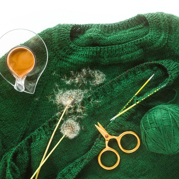 knitting a sweater with knitting needles and a cup of coffee. ba