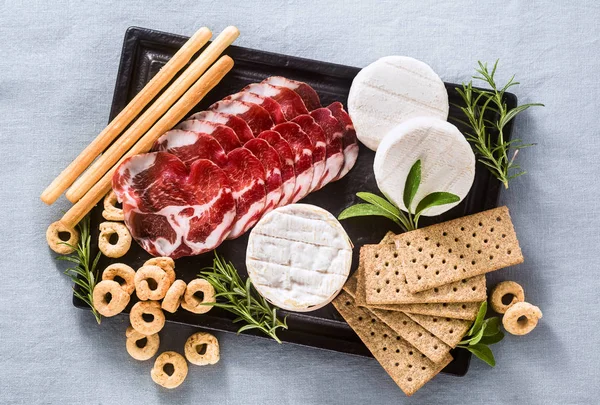 Os cortes frios e o queijo servem-se em uma bandeja em uma mesa com branco — Fotografia de Stock