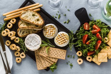 ızgara İtalyan Tomino peyniri beyaz şarap ile bir masada servis,