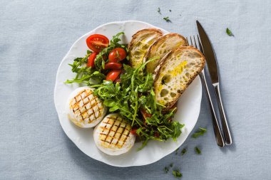 ızgara İtalyan Tomino peyniri arugula sal ile bir masada servis