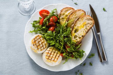 ızgara İtalyan Tomino peyniri arugula sal ile bir masada servis