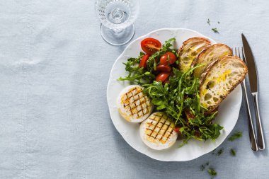 ızgara İtalyan Tomino peyniri arugula sal ile bir masada servis
