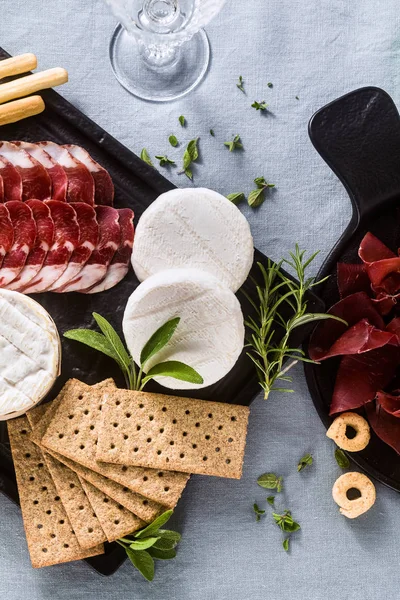 Cold cuts and cheese are served on a tray on a table with white — Stock Photo, Image