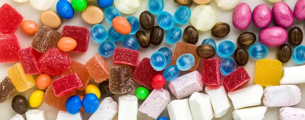 五颜六色的焦糖糖果的横幅散落在桌子上巴 — 图库照片