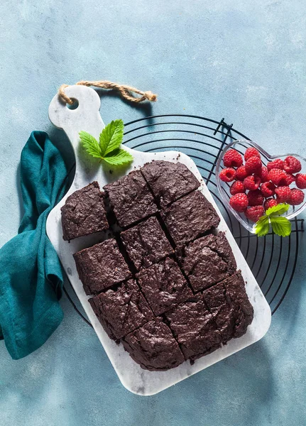 chocolate vegan brownie pie with tahini and fresh raspberries on a blue background