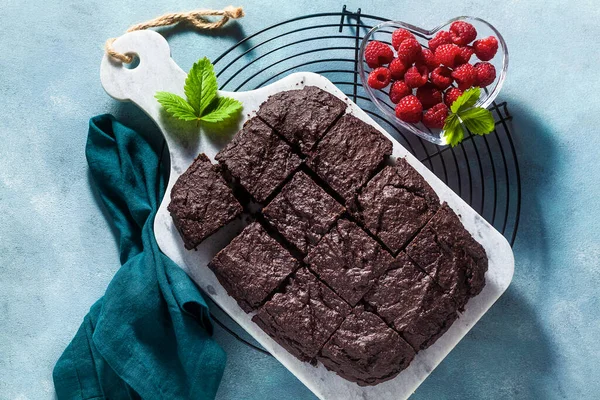 chocolate vegan brownie pie with tahini and fresh raspberries on a blue background