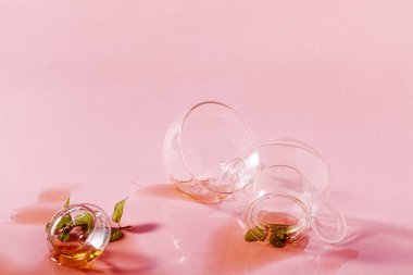 Cam çaydanlığı fırlattı ve pembe arka plana çay döktü. soyut