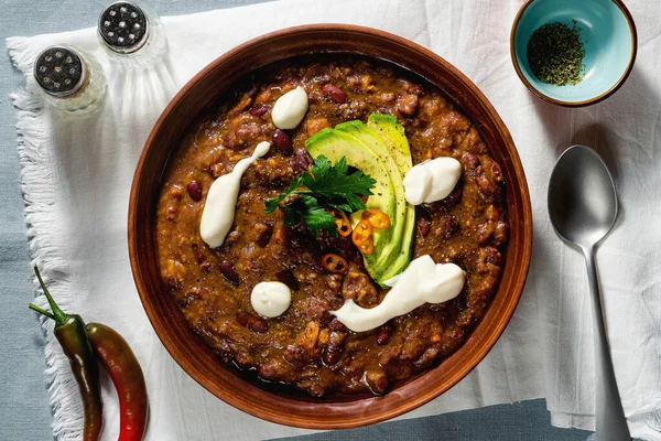 vegan chili soup without meat, with pinto beans and avocado, served with yogurt made from soy on linen tablecloths. healthy eating