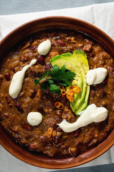 vegan chili soup without meat, with pinto beans and avocado, served with yogurt made from soy on linen tablecloths. healthy eating