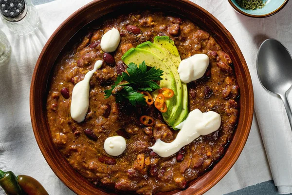 vegan chili soup without meat, with pinto beans and avocado, served with yogurt made from soy on linen tablecloths. healthy eating