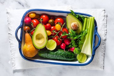 Çok renkli taze yaz sebzeleri ve sebzeleri bir yemek tepsisinde masanın üstünde. Yemek, salata malzemeleri.