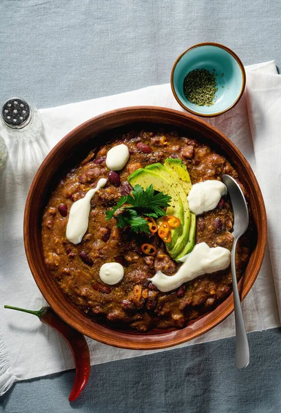vegan chili soup without meat, with pinto beans and avocado, served with yogurt made from soy on linen tablecloths. healthy eating