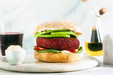 Etsiz vegan burger, avokado, domates ve masada ıspanak ve bardakta kırmızı şarap.
