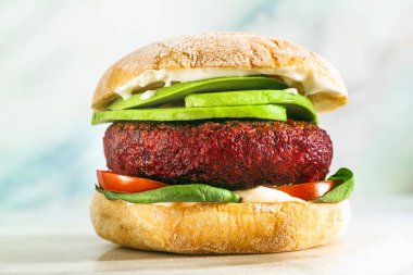 Etsiz vegan burger, avokado, domates ve masada ıspanak ve bardakta kırmızı şarap.