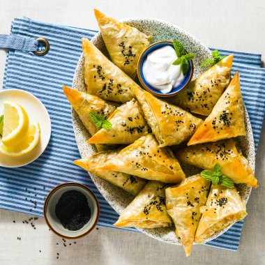 Baharatlı patates ve sebzeli Hint samosası. Yoğurt, nane ve limonla servis ediliyor.