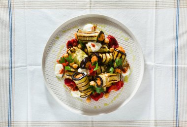 Masanın üzerinde kırmızı dolmalık biber ve baharatlı yoğurt ile ızgara patlıcan dürümü. Lezzetli vegan tarifi