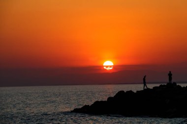 Gün batımında sahilde insan silueti.