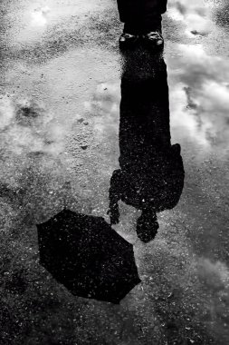 reflection of man with umbrella in the puddle