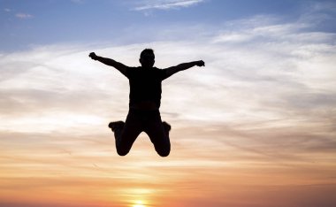 silhouette of jumping man against sunset