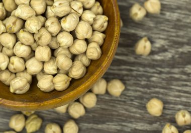 Ahşap arka planda kase içinde çiğ nohut.