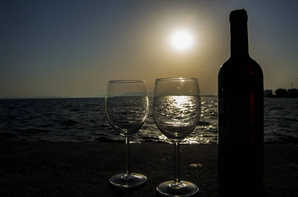 Pair of red wine glasses on the beach.