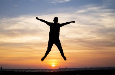 Adam atlamak bir silüet şeklinde günbatımında