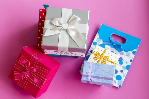 Colorful gift surprise packages, on pink background.