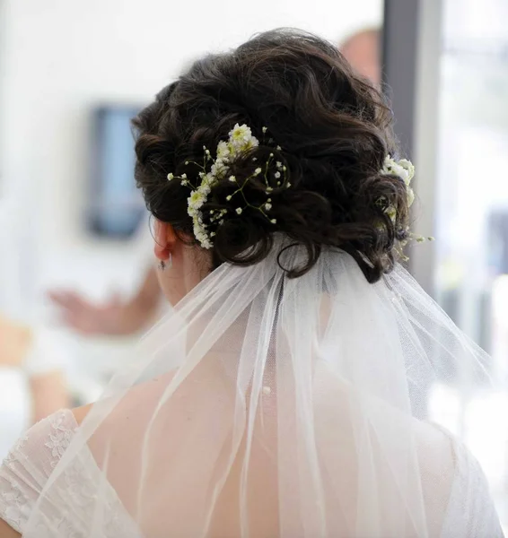 Hair stylist or florist makes the bride a wedding hairstyle