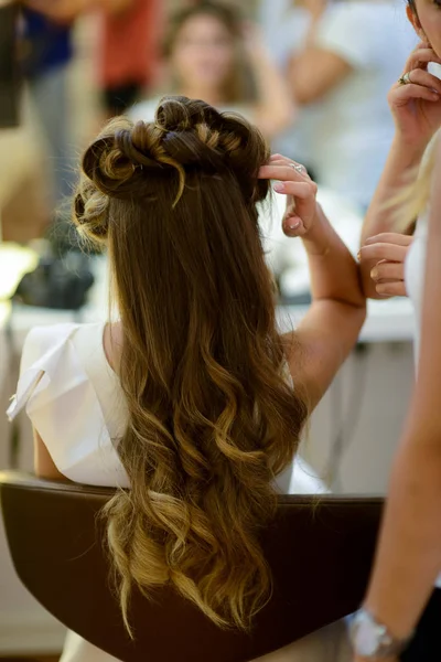 Hair stylist or florist makes the bride a wedding hairstyle