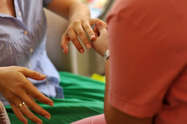 Closeup shot of a woman in a nail salon receiving a manicure by a beautician with nail file. Woman getting nail manicure. Beautician file nails to a customer.