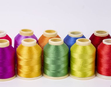 Beyaz arkaplanda renkli iplik bobinleri, dikiş, metin için yer