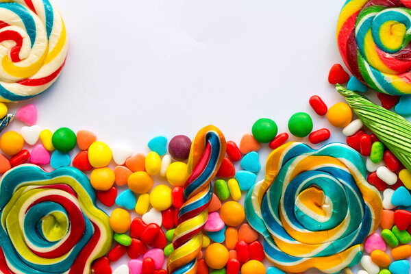 Красочные леденцы и разноцветные круглые конфеты. Вид сверху.