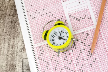 Öğrenciler sınav kağıdına el yazısıyla sınav kağıtları yazarken, okuldaki cevap kağıtları üzerinde kalem çizimi yapıyorlar.