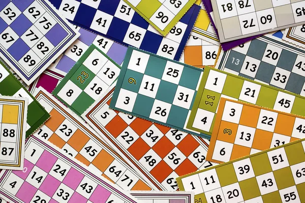 Colorful bingo game cards and numbers on white background, close up, isolated.