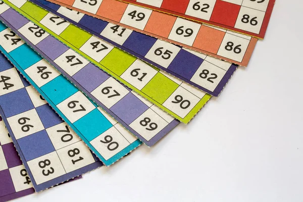 Colorful bingo game cards and numbers on white background, close up, isolated.