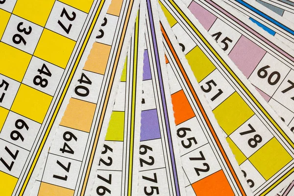 Colorful bingo game cards and numbers on white background, close up, isolated.