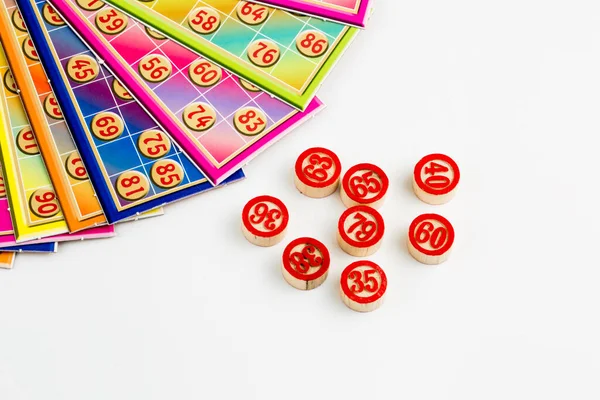 Colorful bingo game cards and numbers on white background, close up, isolated.