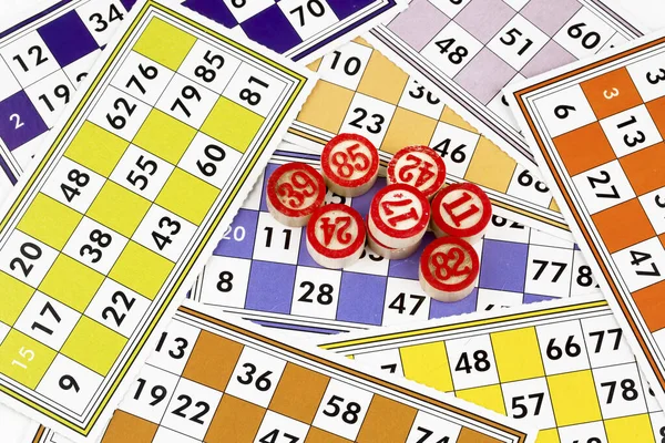 Colorful bingo game cards and numbers on white background, close up, isolated.