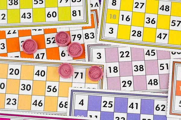 Colorful bingo game cards and numbers on white background, close up, isolated.