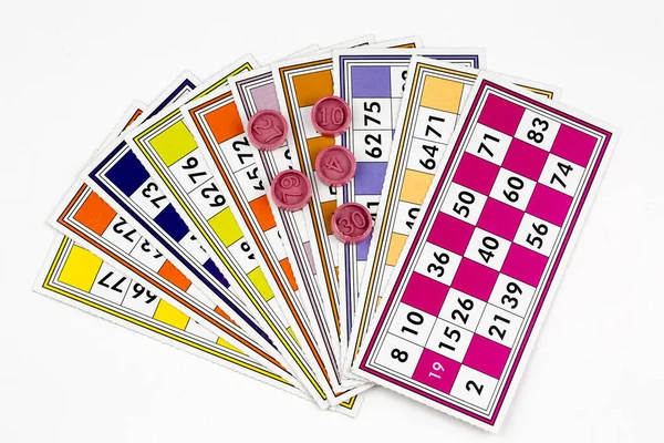 Colorful bingo game cards and numbers on white background, close up, isolated.