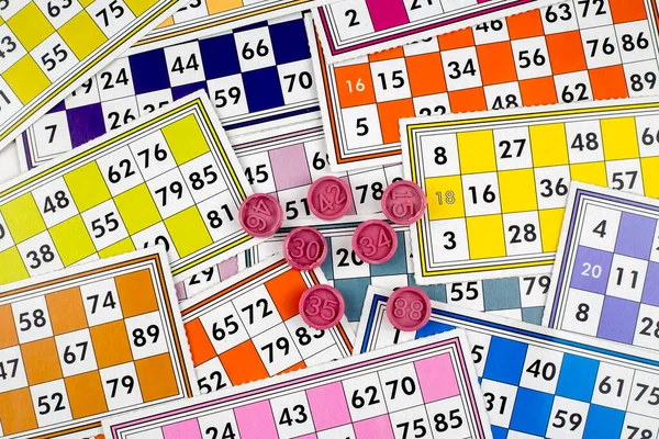 Colorful bingo game cards and numbers on white background, close up, isolated.