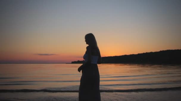 Mooie silhouet zwanger meisje bij zonsondergang gaat op strand — Stockvideo